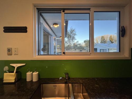 uma cozinha com pia e janela em The Sweet Pea- Room 4 em Hamilton