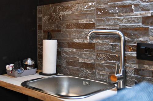 a sink in a bathroom with a brick wall at Appartamenti "UNIQUE" palazzo storico FAENZA in Faenza