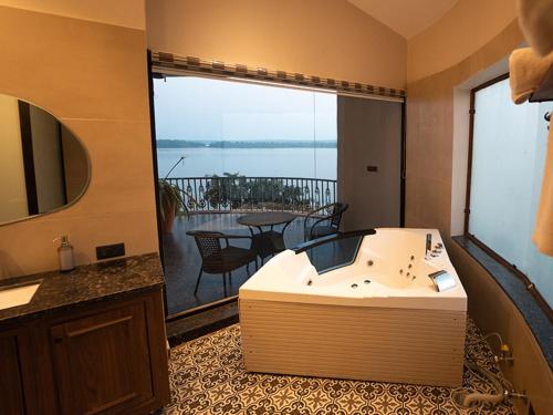 a bathroom with a tub and a balcony with a table at Narwar Lakefront Resort in Shivpurī