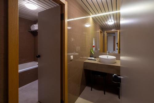 a bathroom with a sink and a tub and a mirror at Hotel 3K Barcelona in Lisbon