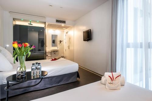 ein Hotelzimmer mit einem Bett und einem Tisch mit Blumen in der Unterkunft Mayerling Hotel in Madrid