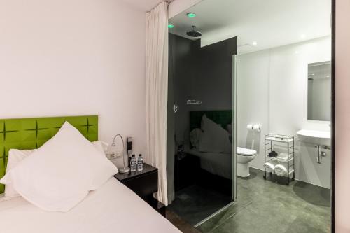 ein Schlafzimmer mit einem Bett und ein Badezimmer mit einer Toilette in der Unterkunft Mayerling Hotel in Madrid