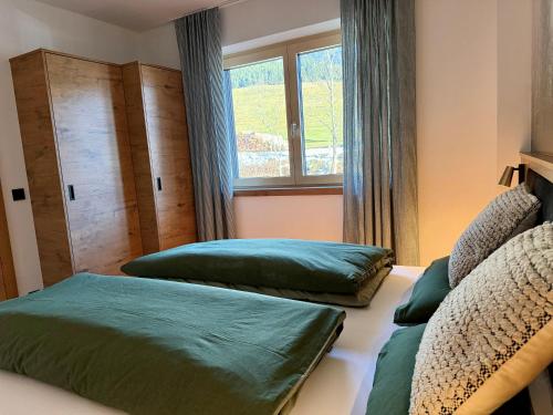 a bedroom with two green beds and a window at Apartment Winkl 65 in Maria Alm am Steinernen Meer