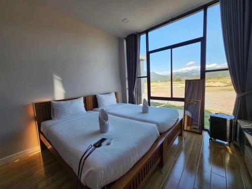 a bedroom with two beds and a large window at เดอนาปัว วิลล่า in Ban Choko