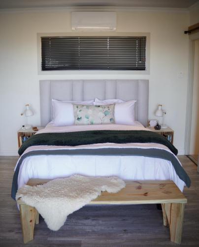 a bedroom with a large white bed with a wooden table at Seaview Container Studio in Gansbaai