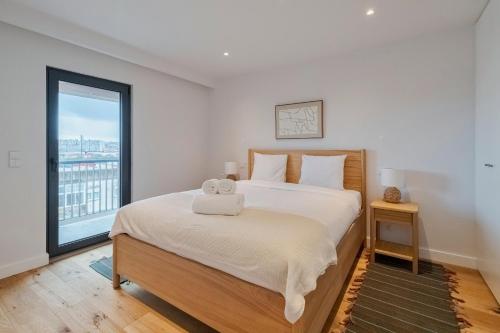 una camera da letto con un grande letto bianco con una finestra di Lume Residence W a Setúbal