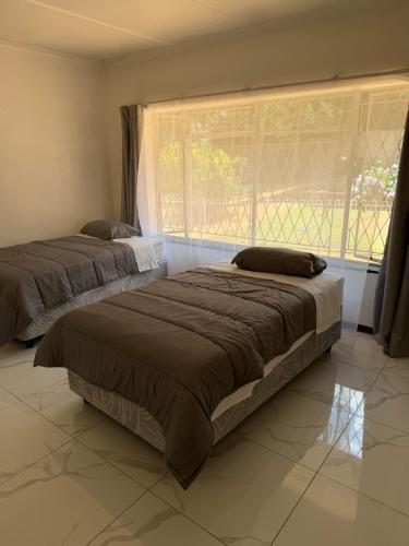 two beds in a room with a large window at Crest Premium in Johannesburg