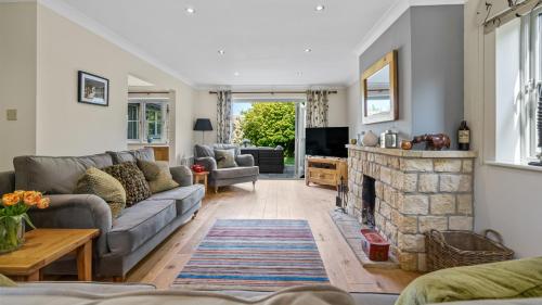 een woonkamer met een bank en een open haard bij Woodside Cottage in Chipping Campden