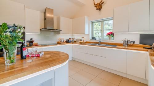 een keuken met witte kasten en een houten aanrechtblad bij Woodside Cottage in Chipping Campden