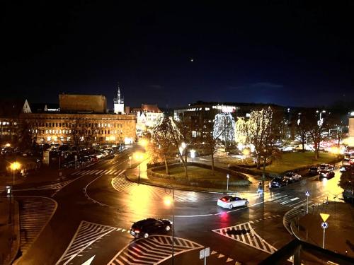 una ciudad iluminada por la noche con coches en una calle en Staromiejskie Retro Apartment by Downtown Apartments, en Gdansk
