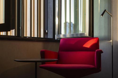 a red chair and a table in a room at Radisson RED Tbilisi in Tbilisi City