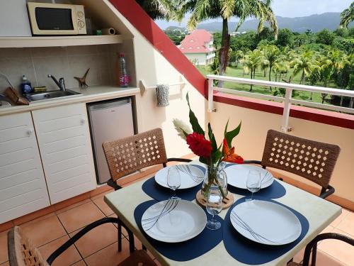 a table with plates and a vase of flowers on it at Village vacances Saint LUCE Studio MARGARITA 35 in Sainte-Luce