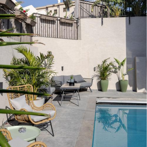an outdoor patio with chairs and a swimming pool at Premium Suite, Pool Access - Sun Circle Complex in Poriyya