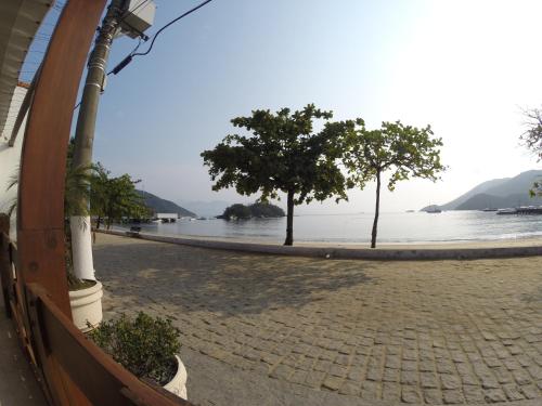 two trees on a sidewalk next to the water at Pousada Agua Viva in Abraão