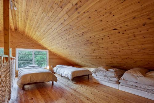 a bedroom with two beds and a wooden ceiling at Tokachi Mikage forest villa in Mikage