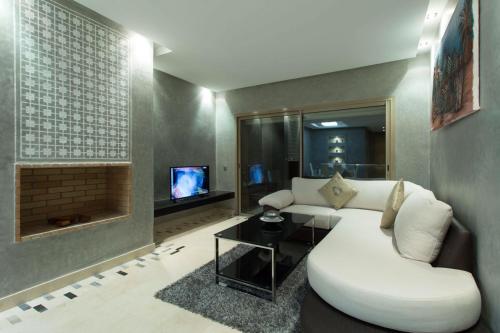 Una sala de estar con un sofá blanco y un televisor. en Prestigia 16, en Marrakech