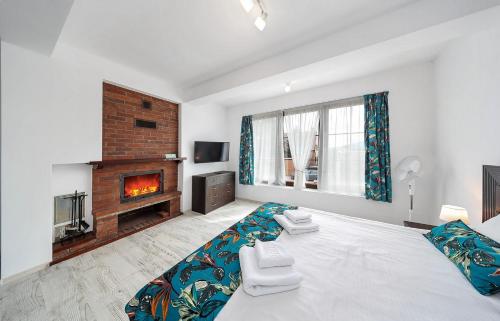 een slaapkamer met een groot bed en een open haard bij Vila Sol in Prejmer