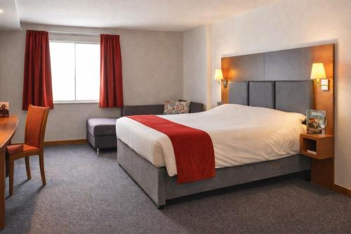 a hotel room with a large bed and a desk at Saram Lodge Lichfield in Lichfield