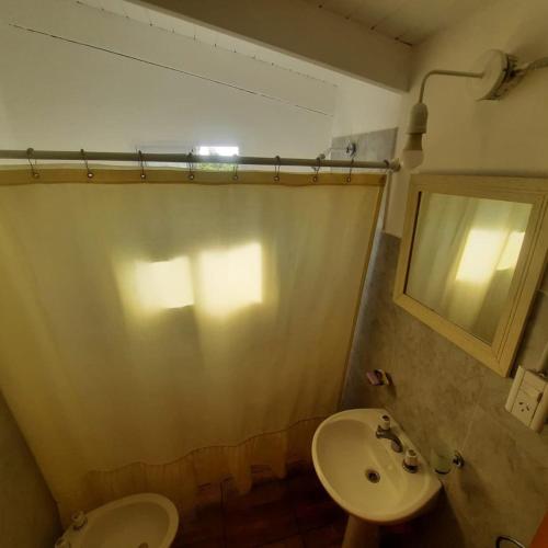 a bathroom with a sink and a toilet and a mirror at Complejo Ayün in Travesía