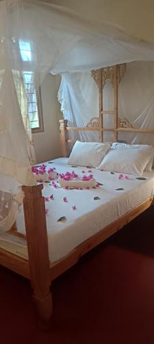 a bed with flowers on it with a canopy at Kua Garden Bungalow in Utende