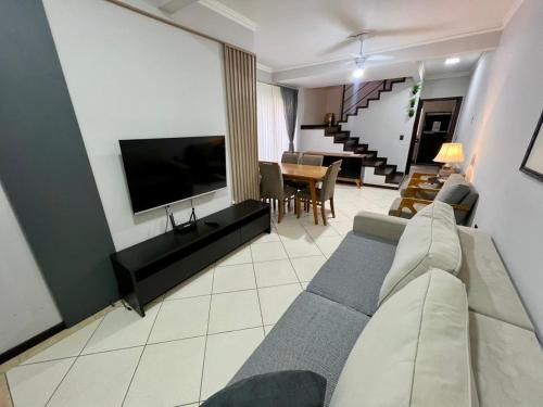 a living room with a couch and a flat screen tv at Rezende Suítes in Balneário Camboriú