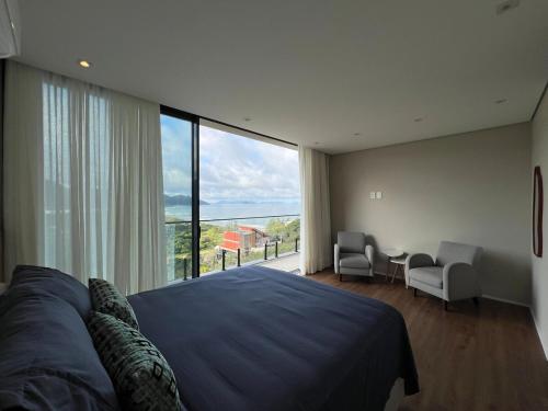 una camera da letto con un letto grande e una grande finestra di Casa Céu do Siriú a Garopaba