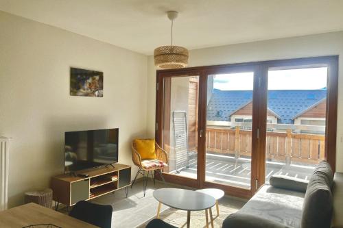 ein Wohnzimmer mit einem Sofa, einem TV und einem Balkon in der Unterkunft T3 apartment with balcony in Briançon in Briançon