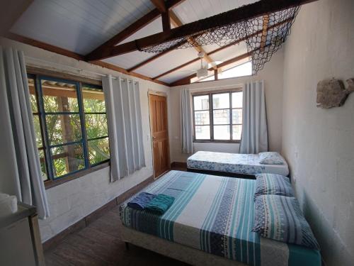 zwei Betten in einem Zimmer mit zwei Fenstern in der Unterkunft Pousada Villa da Nascente in Florianópolis