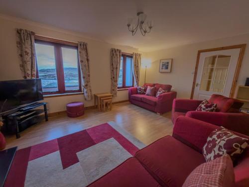 ein Wohnzimmer mit roten Sofas und einem TV in der Unterkunft Tamh Cottage in Tarbert