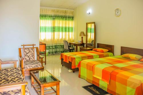 a hotel room with two beds and a chair at Satyodaya Educational Training Centre in Kandy