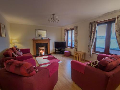 ein Wohnzimmer mit zwei roten Sofas und einem Kamin in der Unterkunft Tamh Cottage in Tarbert
