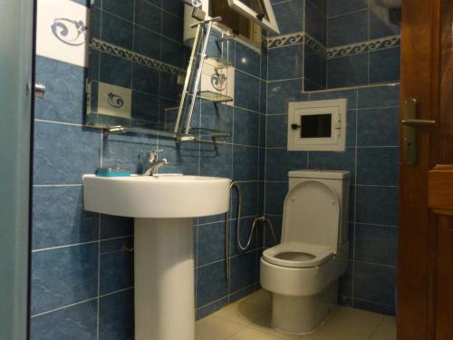 a blue tiled bathroom with a toilet and a sink at Villa Savana in Saly Portudal