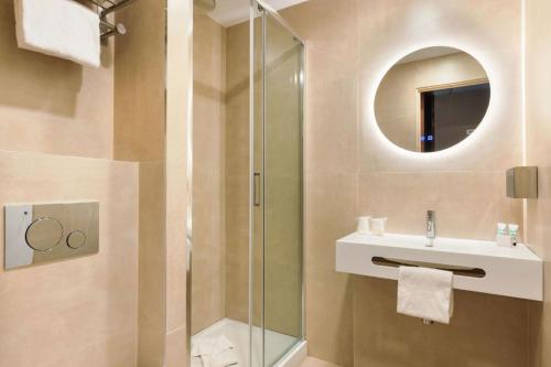 a bathroom with a shower and a sink and a mirror at Hotel Khla Nice in Nice