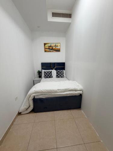 una camera da letto con un letto in una parete bianca di Bienvenue Homes a Dubai