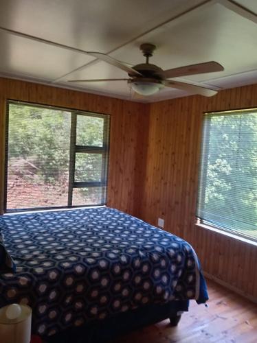 une chambre avec un lit et un ventilateur de plafond dans l'établissement Barberton Troop Cabin, à Barberton