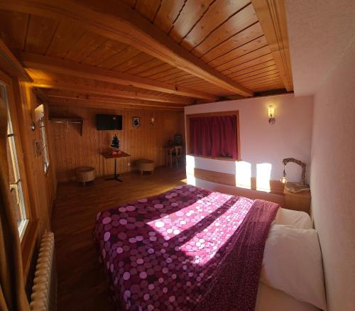 ein Schlafzimmer mit einem Bett mit einer lila Decke darauf in der Unterkunft L'Auberge de la Comballaz in La Comballaz