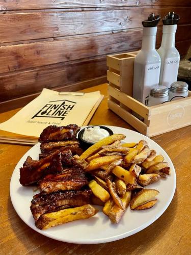 ein Teller mit Fleisch und Pommes auf dem Tisch in der Unterkunft Finish Line Guest House in Borowez