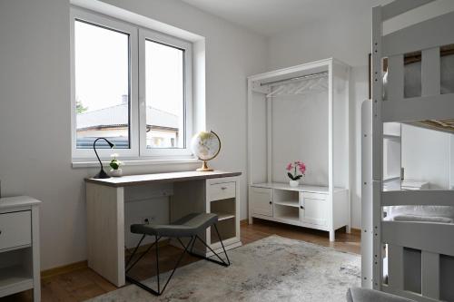 a white bedroom with a desk and a window at Pool & Relax Mukařov in Srbín