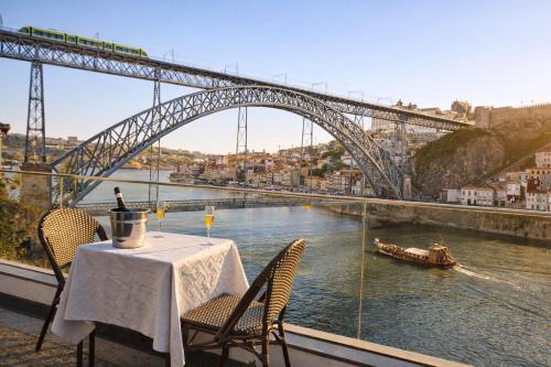 a table with chairs and a bridge over a river at Bridge It - Suites & Views in Vila Nova de Gaia