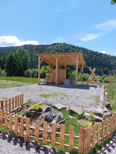 een houten paviljoen in een veld met een hek bij Cabana Mareea -Lunca Bradului in Lunca Bradului