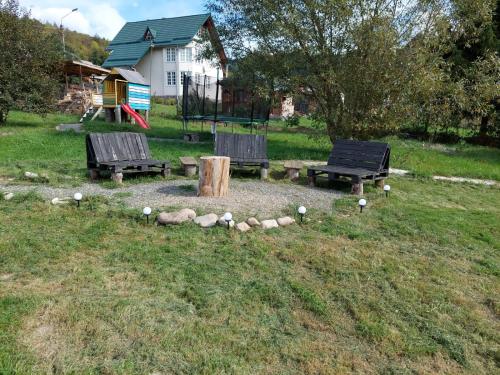 een groep banken in een tuin met een speeltuin bij Cabana Mareea -Lunca Bradului in Lunca Bradului
