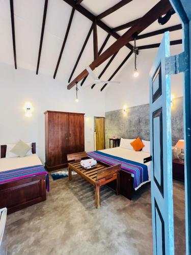 a room with two beds and a wooden table at Krishan Villa in Negombo