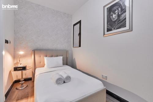 a bedroom with a white bed with two towels on it at bnbmehomes - Al Badia Hillside Village Condo 3 in Dubai