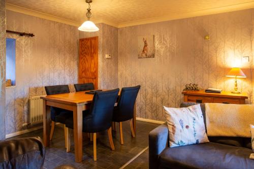 een eetkamer met een tafel en een bank bij Langriggs at Wetheral Cottages in Great Salkeld