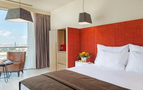 a hotel room with a bed and a desk and a window at Prima Link Hotel in Petaẖ Tiqwa