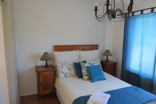 a bedroom with a white bed with blue pillows at Chamomile Cottage 2 in Muizenberg
