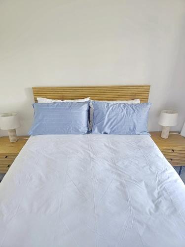 a white bed with blue pillows and two lamps at Laguna Grove 20 in Knysna