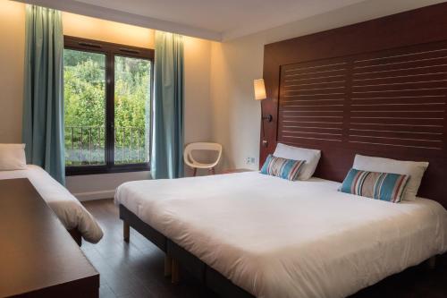 ein Schlafzimmer mit einem großen Bett und einem Fenster in der Unterkunft Hôtel Les Jardins De Sainte-Maxime in Sainte-Maxime