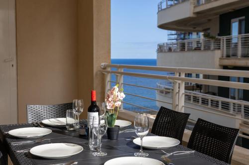 a table with wine glasses and flowers on a balcony at Luxury Apartments with Pool and Terrace, Top Location in Sliema