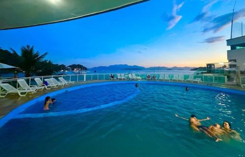 eine Gruppe von Personen, die in einem Pool auf einem Gebäude schwimmen in der Unterkunft Duplex de Frente para a Praia - Angra Inn in Angra dos Reis